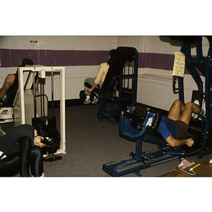 Men and women work out on exercise machines in a gym