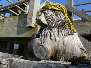 Tree-stump carved like a bear, sitting next to a wooden deck