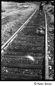 Woman walking down railroad tracks