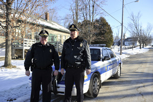 Two New Salem town police officers standing by their patrol car in front of the Stowell Building