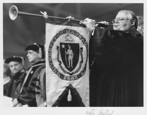 Walter Chesnut standing at UMass commencement playing a herald's trumpet