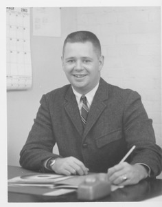 John C. Welles seated at his desk