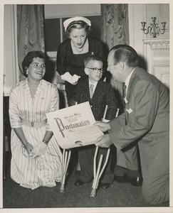 Mayor Robert F. Wagner presenting a proclamation from the American theatre wing to a young boy with forearm crutches