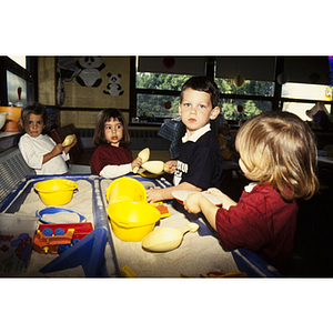 Four children playing with toys in a sandbox