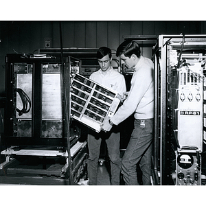 Two co-operative education students load a bank of hard disks into a computer or computer server