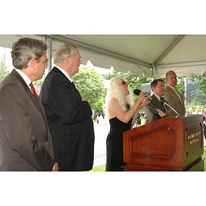 Tish Standencki sings from the podium at the Veterans Memorial groundbreaking ceremony