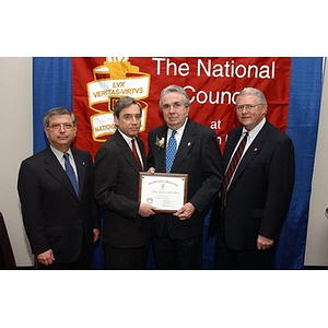 An inductee holds his certificate and poses with others at The National Council Dinner