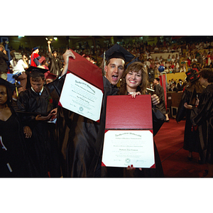 Graduates, Paul Michael Koelling, left, and Stephanie Anne Kinsman, right, hold up their diplomas at commencement