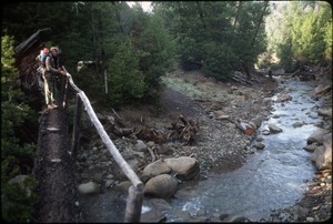 Mark Sommer crossing Salmon Creek in winter with Matthew Tittmanm on his back