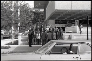 Group of men in suits gathered on steps of brutaist building