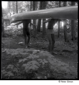 Camp Arcadia: campers carrying a canoe through the woods