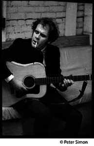 Tim Hardin smoking a cigarette and playing guitar at the Unicorn Coffee House, Boston, Mass.