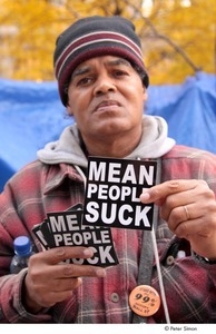 Occupy Wall Street: man holding 'mean people suck' stickers