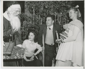 Man dressed as Santa Claus with clients in front of Christmas tree