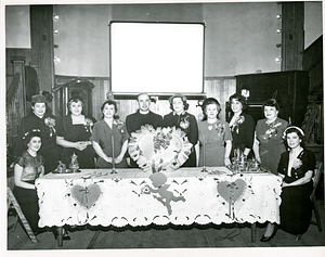 Fr. John Silva standing with women behind table