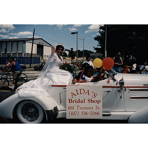 A woman in a bridal gown sits in a car during a parade for the Festival Puertorriqueño