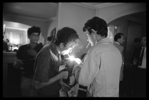 Unidentified man at a reception lighting a cigarette for Bob Dylan, Newport Folk Festival
