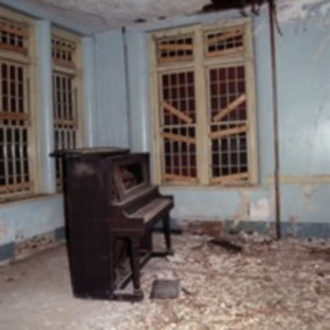 Piano in room with boarded windows