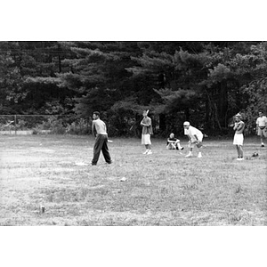 Inquilinos Boricuas en Acción employees playing baseball on a grassy field during a staff outing.