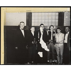 Three Boys' Club members pose with Richard B. K. McLanathan, at center, and two unidentified men, holding their basketball tournament trophies