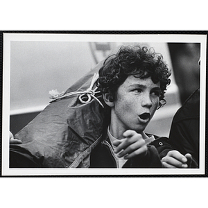 A teenage boy from the Boys' Clubs of Boston carrying something on his shoulder and pointing to the front while talking