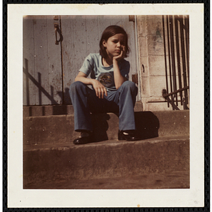 A girl sitting on the front steps at the South Boston Boys' Club, resting her head in her hand