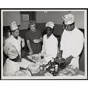 Members of the Tom Pappas Chefs' Club and an unidentified woman participate in a cooking demonstration in Roxbury, Massachusetts