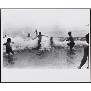 Boys pose as the they play in the surf on a beach