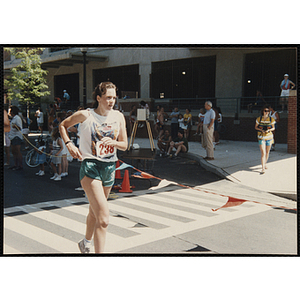 A woman runs past spectators during the Battle of Bunker Hill Road Race