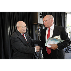 Dr. George J. Kostas shakes hands with Ralph Patuto at the groundbreaking ceremony for the George J. Kostas Research Institute for Homeland Security, located on the Burlington campus of Northeastern University