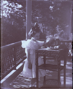 Girl viewing a goldfish bowl on a house porch, Mashpee, Mass.