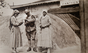 Two Red Cross workers offering cigarettes to a soldier outside a canteen
