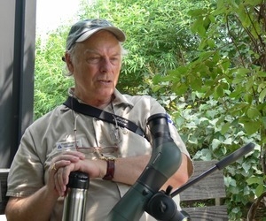 Rives McGinley (Audubon Society volunteer) seated on a bench with birding equipment, Wellfleet Bay Wildlife Sanctuary