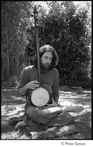 Krisha Das: portrait of the vocalist with Amazing Grace and member of the Ram Dass satsang, seated in a lotus position with an dotara