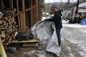 Aftermath of the Congregational Church fire in West Cummington, Mass.: man pulling a tarp away from the charred remains of the church bell