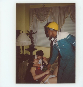 A Photograph of Marsha P. Johnson Wearing a Construction Hat and Tracksuit, with Two Unknown People