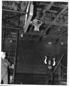 Suffolk University Athletics Director James E. Nelson (1978-2013), testing basketball hoop as new gym is completed