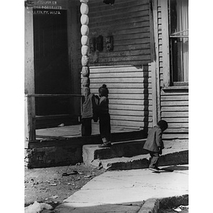 Two African American children play outside of a dilapidated house on Oakborn Avenue, Roxbury, Mass.
