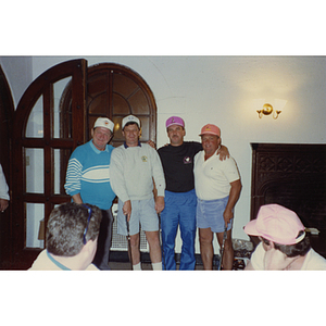 A four-man golf team posing for the camera while others look on at a Boys & Girls Club Golf Tournament