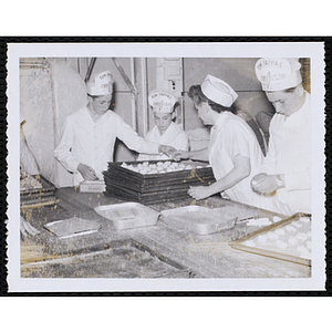 Members of the Tom Pappas Chefs' Club prepare foodstuffs on sheet pans in a kitchen