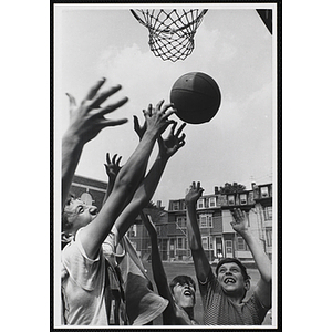 Boys jockey for a rebound during an outdoor pickup basketball game