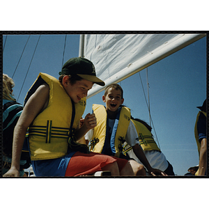 Two boys sit on a sailboat