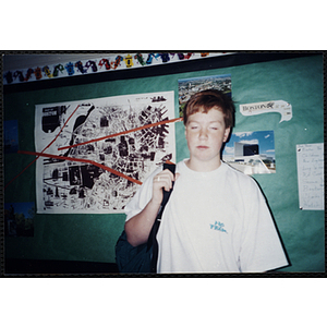 A boy stands in front of a Boston-themed bulletin board at a Tri-Club event