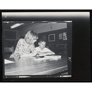 A Teacher helping a student with his work in the library