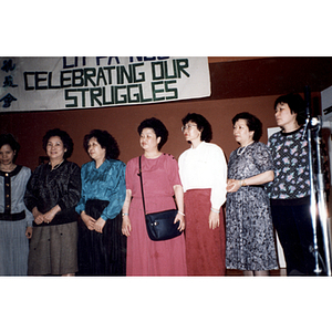Chinese Progressive Association members stand beneath a sign with the words "Celebrating our Struggles"