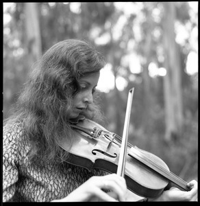 Close-up of woman playing a fiddle in a eucalyptus grove