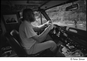 Ram Dass in his van: Ram Dass in the driver's seat with a picture of of Neem Karoli Baba behind him