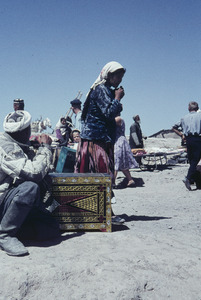 Man squatting near a large ornamental chest at a market