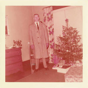 Joseph Lyles standing by a Christmas tree, c. 1955