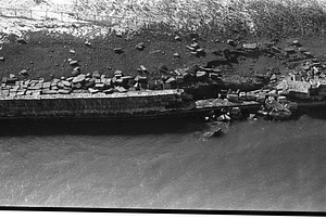 Damaged brick wall alongside body of water